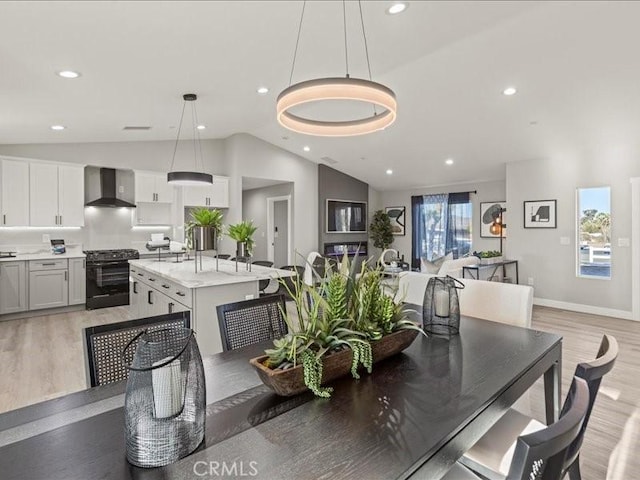 dining space featuring vaulted ceiling, sink, and light hardwood / wood-style floors