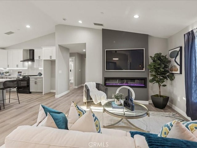 living room with lofted ceiling, a fireplace, and light hardwood / wood-style flooring