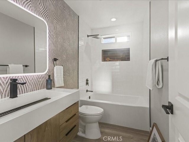 full bathroom featuring wood-type flooring, toilet, vanity, and tiled shower / bath