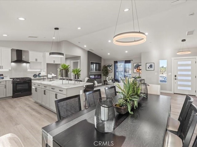 dining area featuring lofted ceiling and light hardwood / wood-style floors