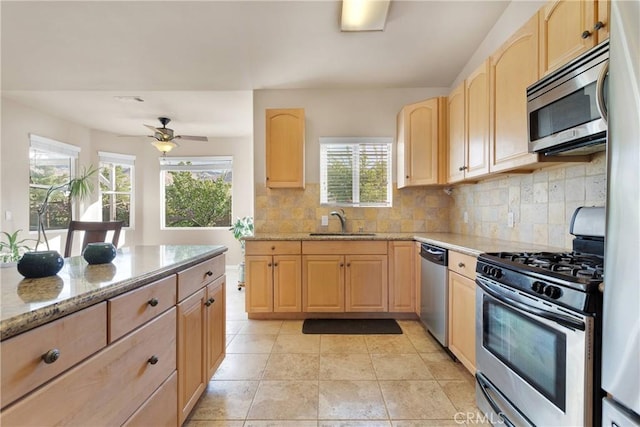 kitchen with stainless steel appliances, light brown cabinets, light stone counters, and sink