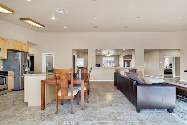 kitchen with ceiling fan, appliances with stainless steel finishes, light brown cabinetry, and a center island