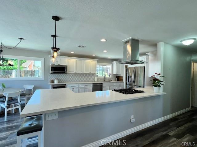 kitchen with backsplash, black appliances, island exhaust hood, hanging light fixtures, and white cabinets