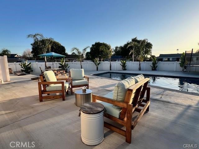 patio terrace at dusk featuring a fenced in pool