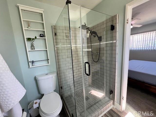 bathroom featuring toilet, ceiling fan, hardwood / wood-style floors, and a shower with door