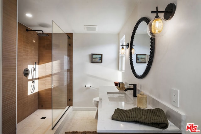 bathroom featuring toilet, a tile shower, tile patterned floors, and vanity