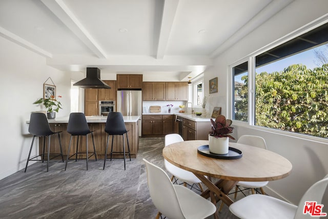 dining space with beam ceiling and sink