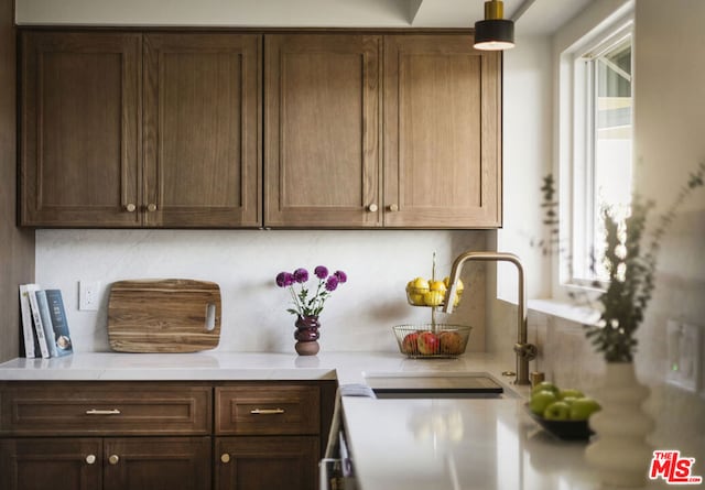 kitchen with backsplash, sink, and dark brown cabinetry