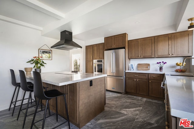 kitchen with appliances with stainless steel finishes, island exhaust hood, a kitchen breakfast bar, sink, and beam ceiling