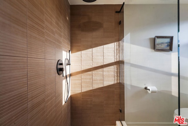 room details featuring toilet and a tile shower