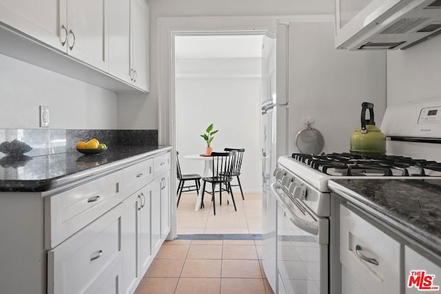 kitchen with extractor fan, gas range gas stove, white cabinetry, light tile patterned floors, and dark stone counters