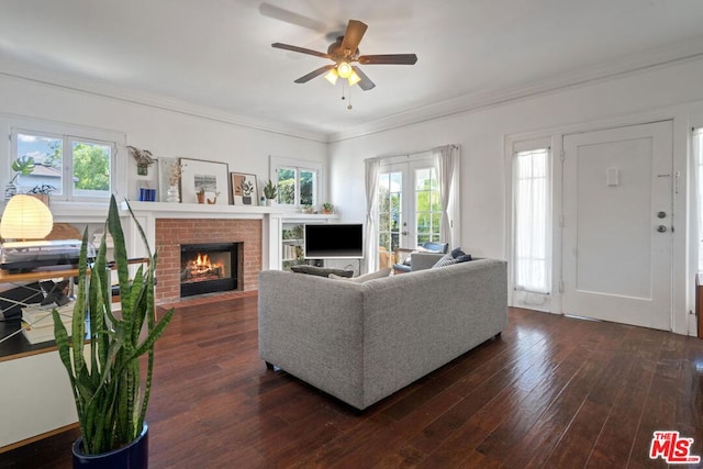 living room featuring ceiling fan, dark hardwood / wood-style flooring, a fireplace, french doors, and ornamental molding