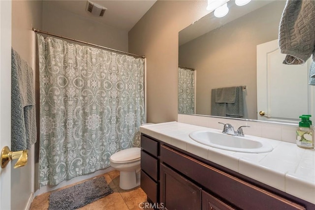 bathroom with toilet, vanity, and tile patterned flooring