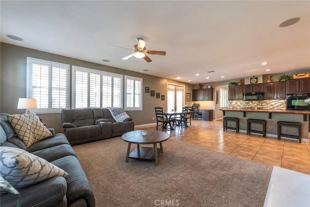 living room featuring ceiling fan, sink, and light tile patterned floors