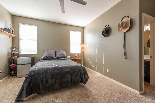 carpeted bedroom featuring ceiling fan, ensuite bathroom, and stainless steel refrigerator