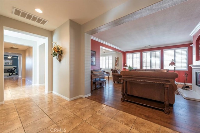 living room featuring a healthy amount of sunlight, light tile patterned flooring, and crown molding