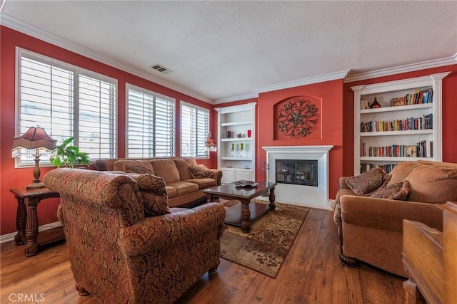 living room with wood-type flooring, built in features, and crown molding