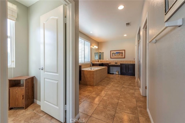 bathroom featuring tile patterned floors and a relaxing tiled tub