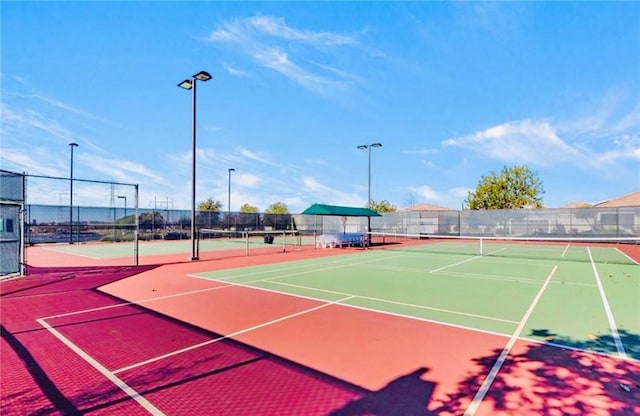 view of tennis court with community basketball court and fence