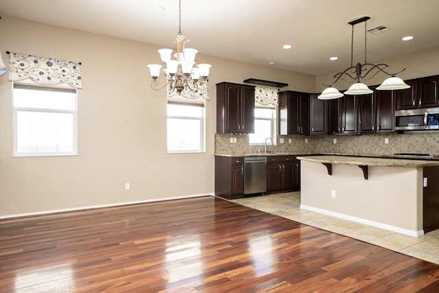 kitchen featuring appliances with stainless steel finishes, light wood-type flooring, a breakfast bar, and decorative backsplash