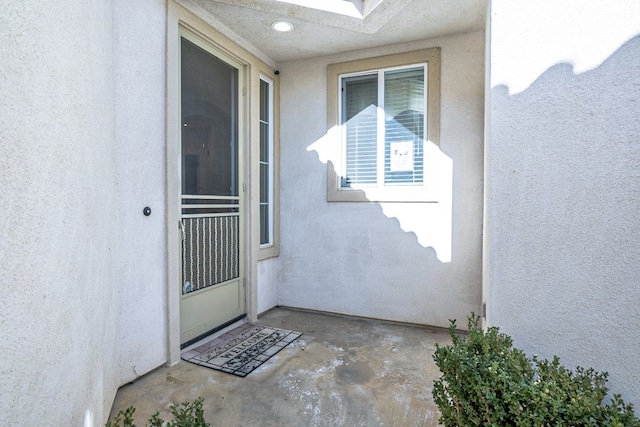 property entrance with a patio and stucco siding