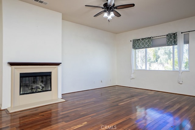 unfurnished living room featuring a ceiling fan, wood finished floors, and a glass covered fireplace