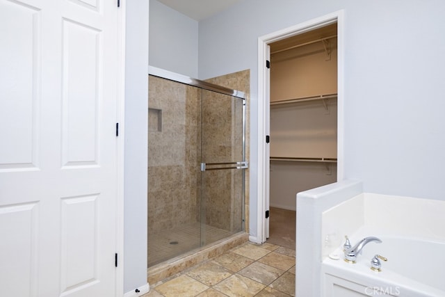 bathroom with a stall shower, a walk in closet, and a bath