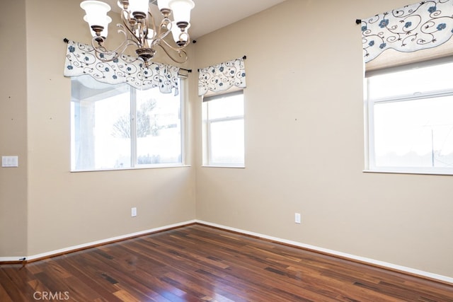 unfurnished dining area with a notable chandelier, dark wood finished floors, and baseboards