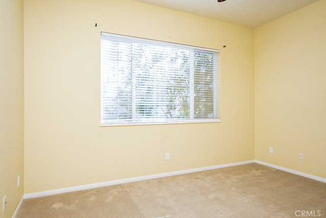 unfurnished room with light colored carpet and baseboards