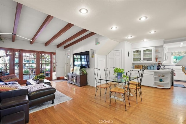 dining area featuring light hardwood / wood-style flooring and vaulted ceiling with beams