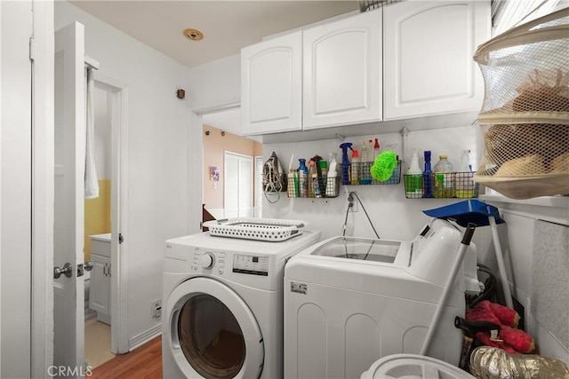 laundry area featuring washing machine and dryer, hardwood / wood-style floors, and cabinets