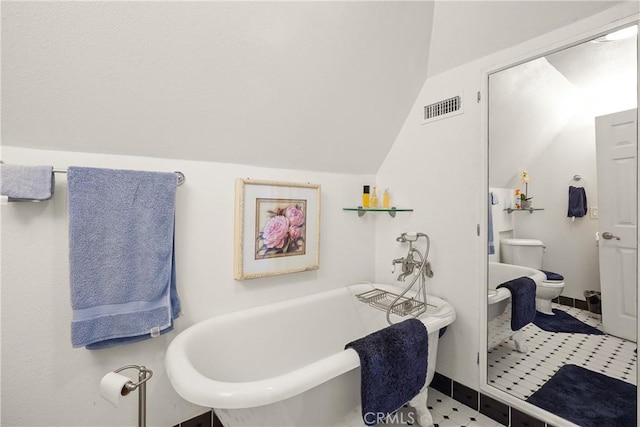 bathroom featuring vaulted ceiling, a tub, and toilet