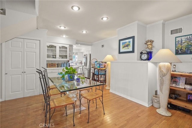 dining area with light hardwood / wood-style floors and ornamental molding