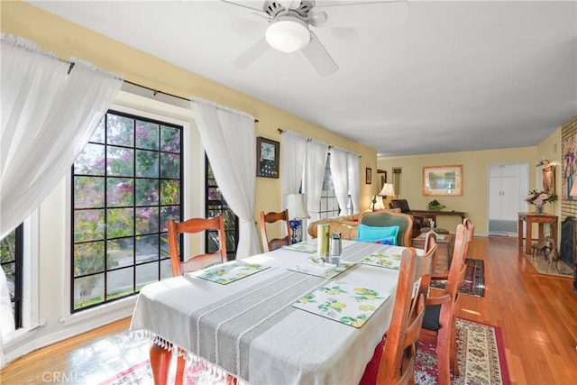 dining area with light wood-type flooring, ceiling fan, and a healthy amount of sunlight