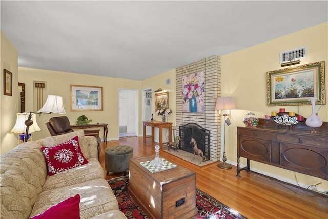 living room with wood-type flooring and a brick fireplace