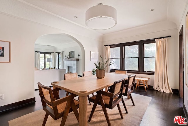 dining space with a brick fireplace and dark wood-type flooring