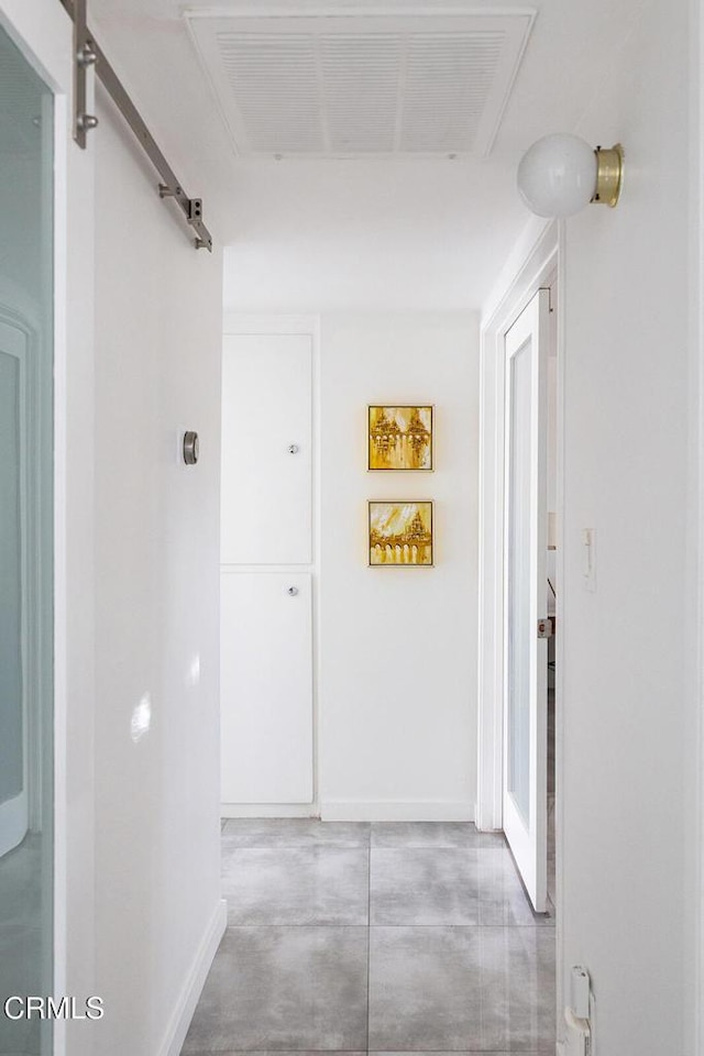 hall featuring a barn door and concrete flooring