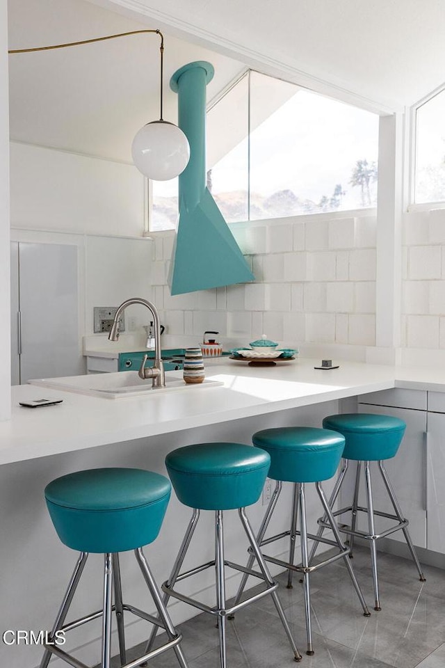 kitchen with kitchen peninsula, backsplash, and a breakfast bar area