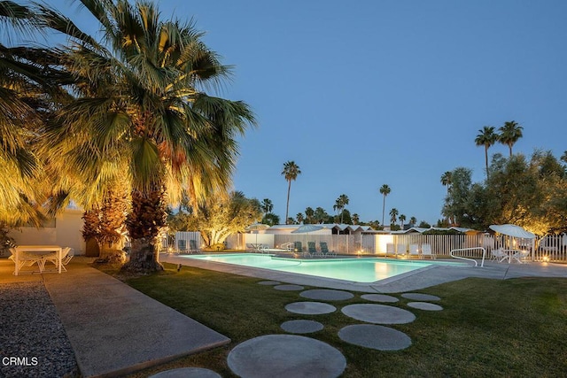 pool at dusk with a yard and a patio