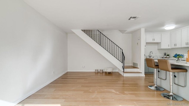 kitchen featuring a breakfast bar, sink, white cabinetry, and light hardwood / wood-style floors