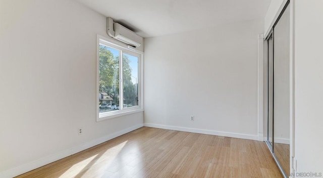 unfurnished bedroom with light hardwood / wood-style flooring, a closet, and a wall mounted AC