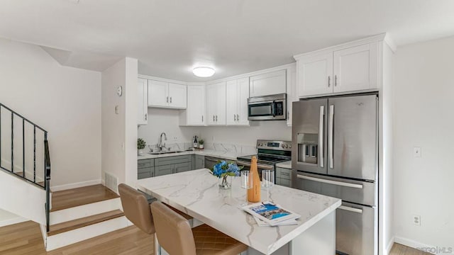 kitchen with light stone countertops, white cabinets, appliances with stainless steel finishes, and sink