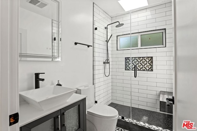 bathroom with toilet, vanity, and a shower with shower door