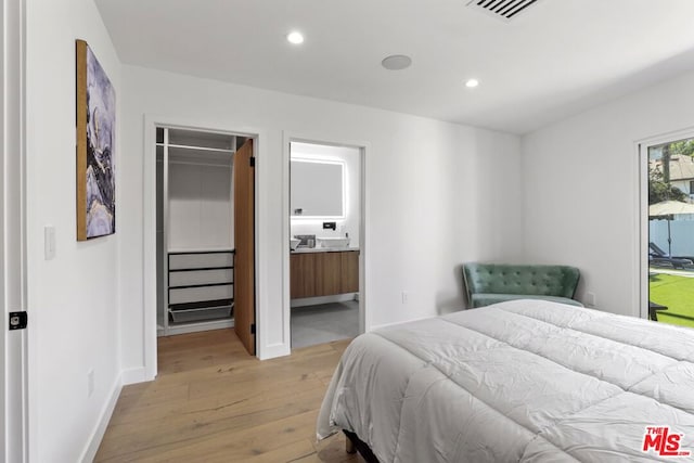 bedroom featuring ensuite bathroom, a closet, and light hardwood / wood-style flooring