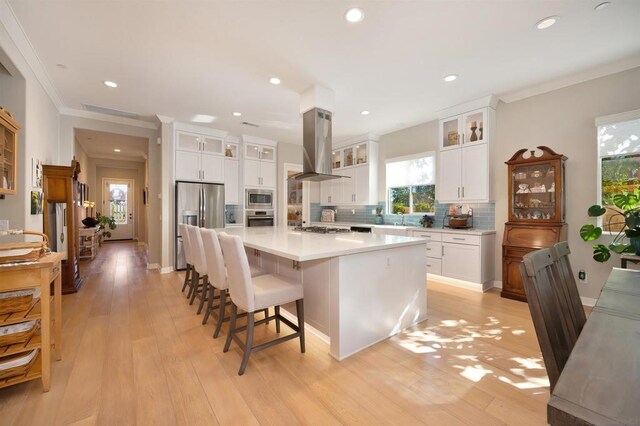 kitchen featuring white cabinetry, light hardwood / wood-style floors, extractor fan, stainless steel appliances, and a center island