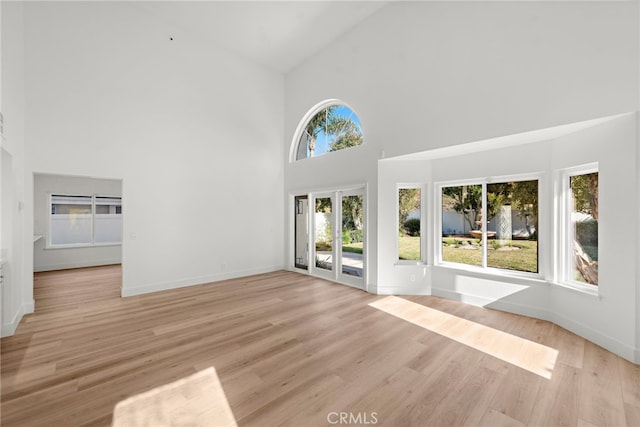 unfurnished living room featuring a wealth of natural light, light hardwood / wood-style floors, and high vaulted ceiling