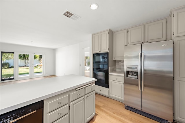 kitchen with white cabinets, black appliances, and light hardwood / wood-style flooring