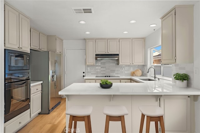 kitchen featuring sink, black appliances, a breakfast bar, and tasteful backsplash