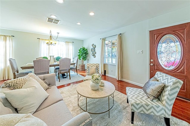 living room with plenty of natural light, light hardwood / wood-style flooring, and an inviting chandelier