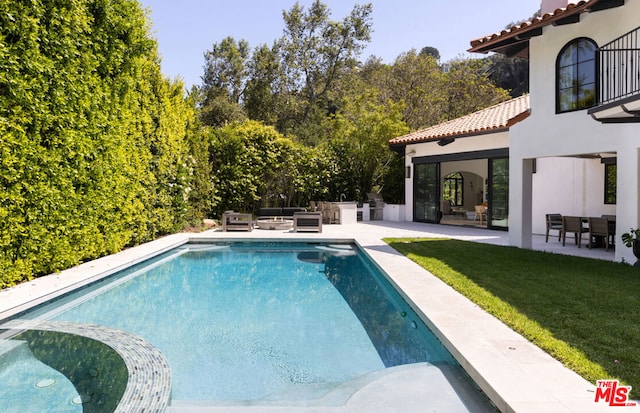 view of pool featuring a lawn, an outdoor kitchen, an outdoor living space, and a patio area